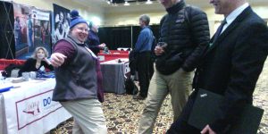Jane, Brain, and friend, touch feet as a safe greeting at Convocation