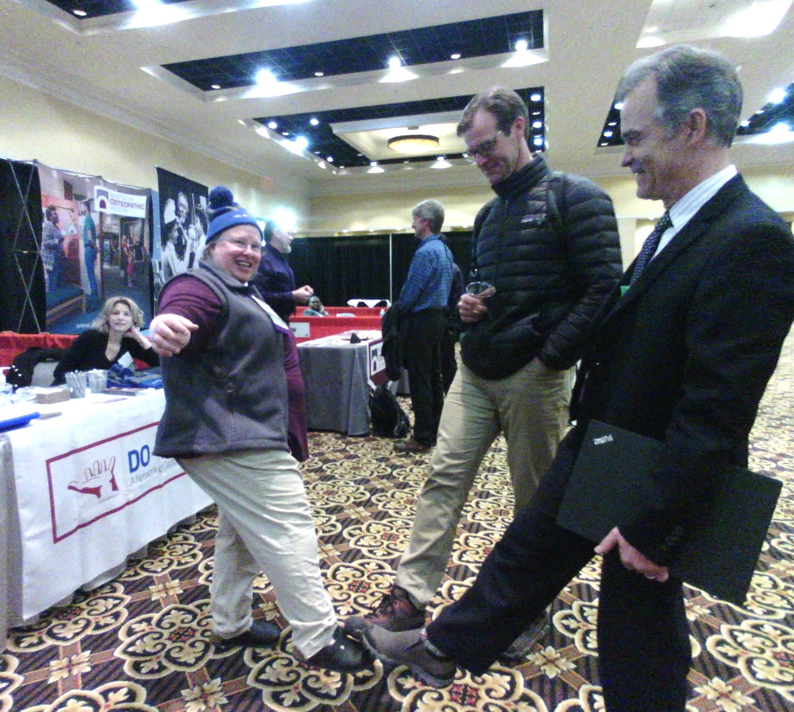 Jane, Brain, and friend, touch feet as a safe greeting at Convocation